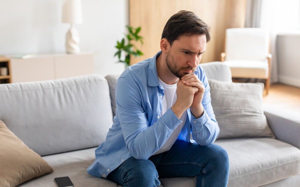 Man on a couch worried about being charged with murder